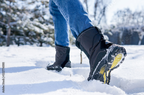 male or female winter boots walking on snowy sleet road 
