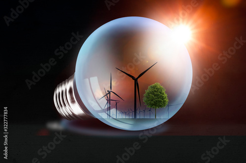 Leuchtende Glühbirne auf dunklem Hintergrund mit Windpark Spiegelung - Konzept