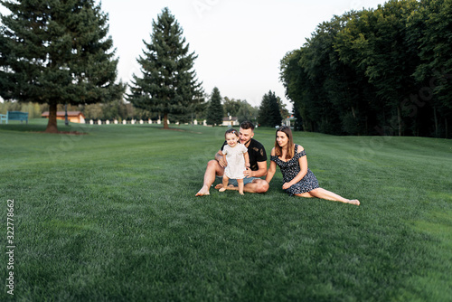 Portrait of a young family on a green meadow