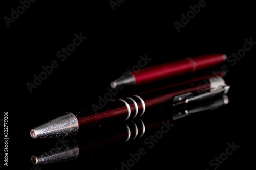 Group of two whole red writing ballpoint pen isolated on black glass