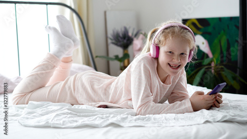 Wallpaper Mural modern life of generation Z. teenage girl in pajamas and headphones in the room on the bed listens to music from a smartphone. Torontodigital.ca