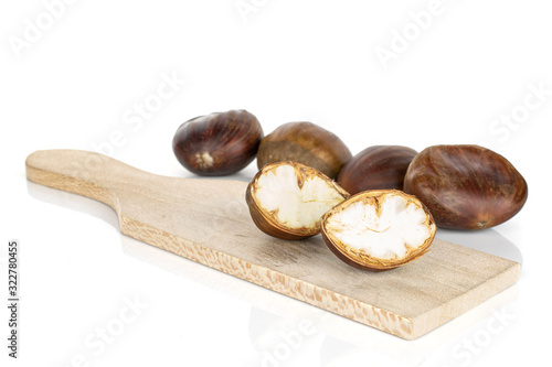 Group of four whole two halves of edible brown chestnut on wooden cutting board isolated on white background photo