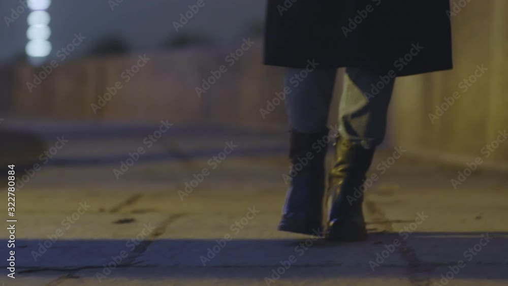 Close up of unrecognizable woman wearing massive black boots and blue jeans going along paved road Close up of unrecognizable woman wearing massive black boots and blue jeans going along paved road
