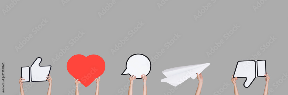 Hands holding the signs of social media on grey background, flyer. Copyspace for your text or image, advertising. Showing meaning, gadgets, modern technologies, comments, message, interactions. Hands holding the signs of social media on grey background, flyer. Copyspace for your text or image, advertising. Showing meaning, gadgets, modern technologies, comments, message, interactions.