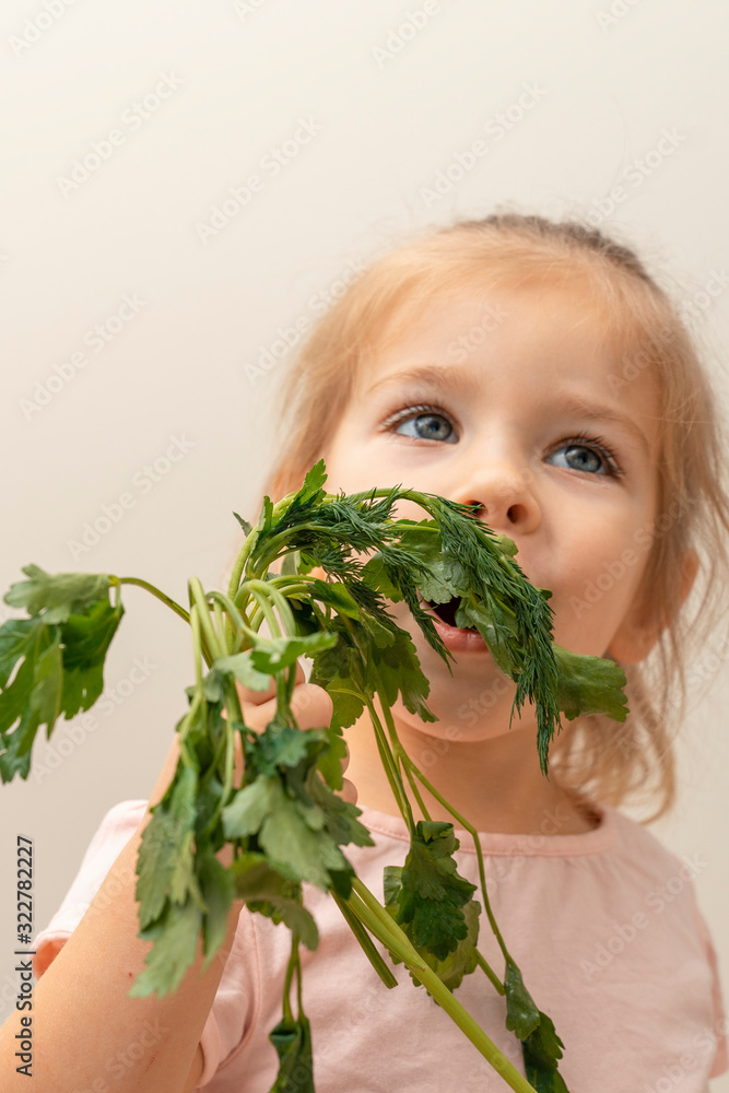a girl of three years is happy to eat a bunch of parsley. focus on parsley. baby food problem a girl of three years is happy to eat a bunch of parsley. focus on parsley. baby food problem