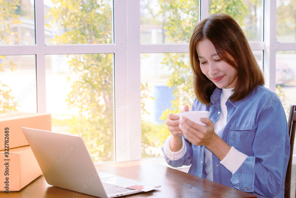 Beautiful Asian woman in casual using laptop technology for running small business start up marketing with cardboard box logistic delivery. young entrepreneur using credit card shopping payment, Beautiful Asian woman in casual using laptop technology for running small business start up marketing with cardboard box logistic delivery. young entrepreneur using credit card shopping payment,