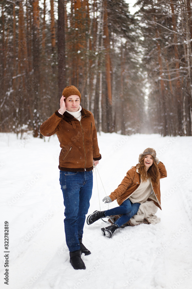 Happy lovers a guy and a girl who love each other hug, kiss, laugh, rage and walk in warm jackets in winter against the background of a snowy forest, a friendly family fun walk Happy lovers a guy and a girl who love each other hug, kiss, laugh, rage and walk in warm jackets in winter against the background of a snowy forest, a friendly family fun walk
