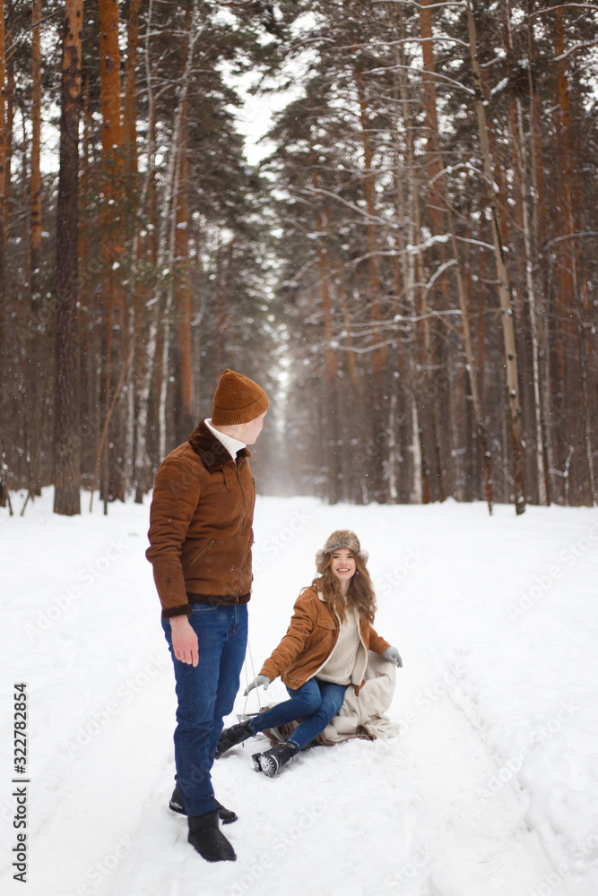 Happy lovers a guy and a girl who love each other hug, kiss, laugh, rage and walk in warm jackets in winter against the background of a snowy forest, a friendly family fun walk Happy lovers a guy and a girl who love each other hug, kiss, laugh, rage and walk in warm jackets in winter against the background of a snowy forest, a friendly family fun walk