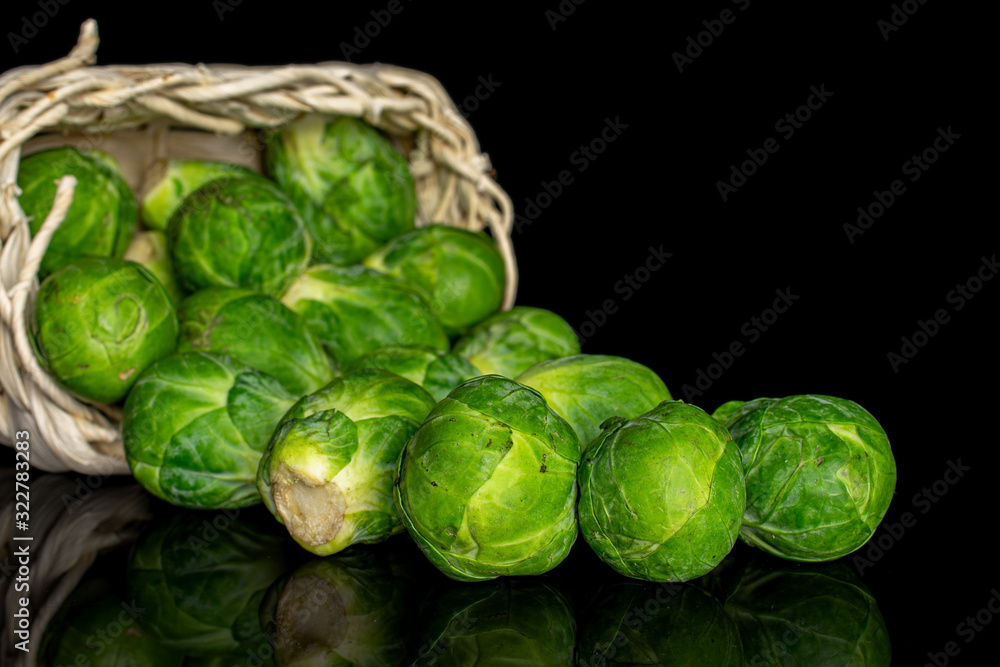 Fototapeta premium Lot of whole fresh green brussels sprout in bast basket isolated on black glass