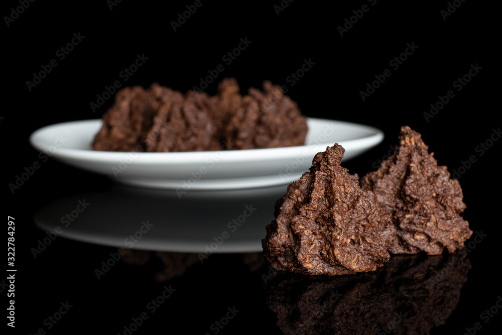 Group of six whole homemade brown coconut cocoa biscuit on white ceramic plate isolated on black glass Group of six whole homemade brown coconut cocoa biscuit on white ceramic plate isolated on black glass