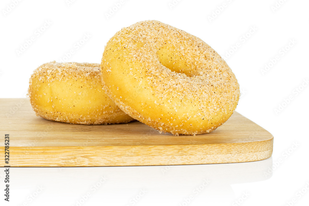 Group of two whole sweet golden mini cinnamon donut on bamboo cutting board isolated on white background Group of two whole sweet golden mini cinnamon donut on bamboo cutting board isolated on white background