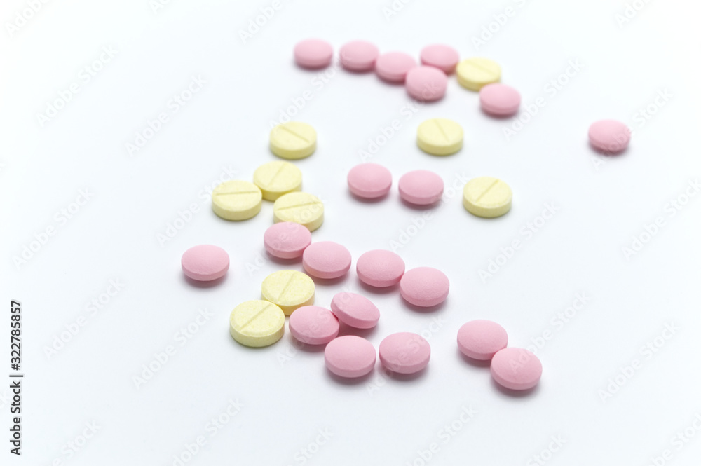 Prescription drugs, pills or tablets of different colors between pink and yellow. On white background. Selective focus.