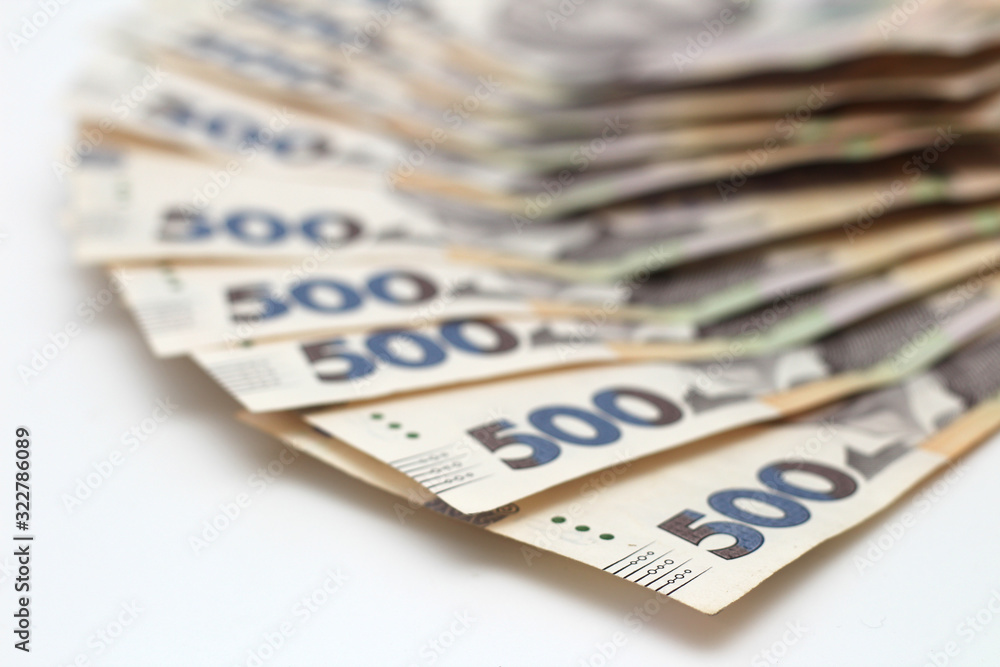 A lot of new banknotes in denominations of 500 Ukrainian hryvnias isolated on a white background with shadow. European money exchange. Ukraine currency. Selective focus A lot of new banknotes in denominations of 500 Ukrainian hryvnias isolated on a white background with shadow. European money exchange. Ukraine currency. Selective focus