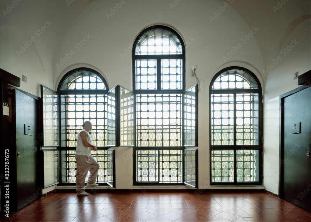 Prisoner in jail looking outside through large windows