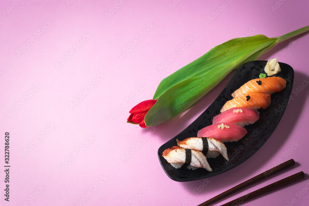 Sushi set with flower on pink background. Salmon, tuna and eel sashimi nigiri. Valentines Day (14 February), Mother's day, Woman's day (8 March), date or spring concept. Japanese food. Copy space