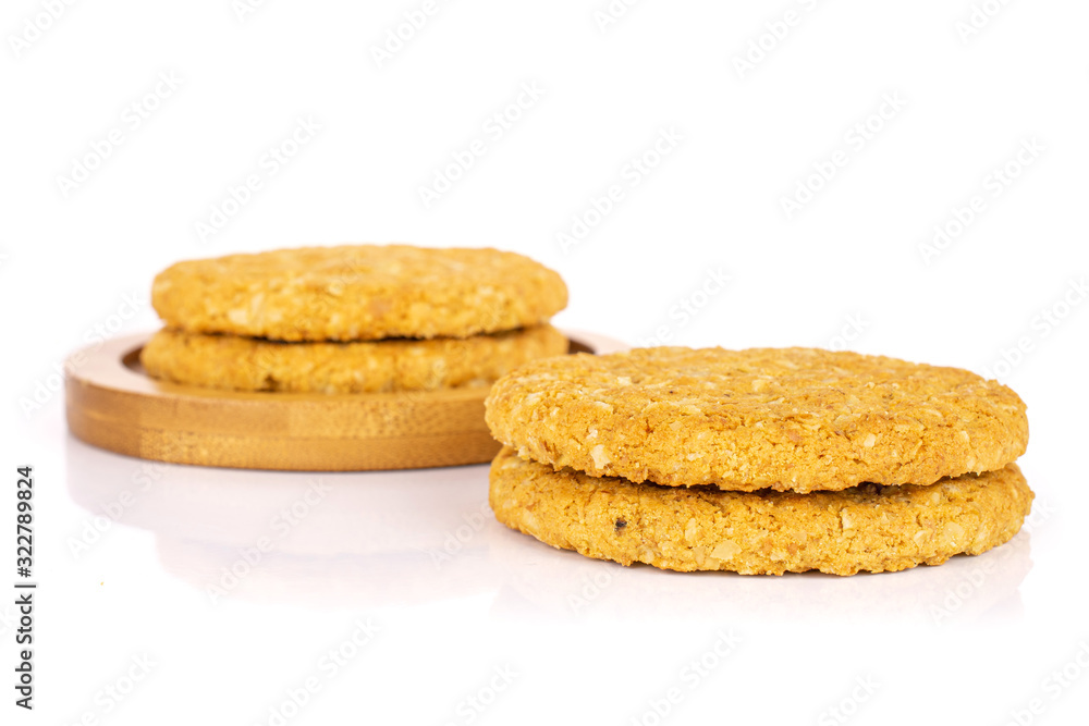 Group of four whole sweet golden oat cookie on bamboo coaster isolated on white background Group of four whole sweet golden oat cookie on bamboo coaster isolated on white background