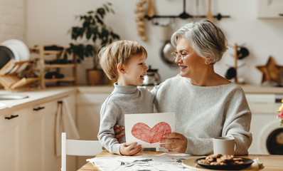 happy family grandson child congratulates grandmother on holiday and gives card