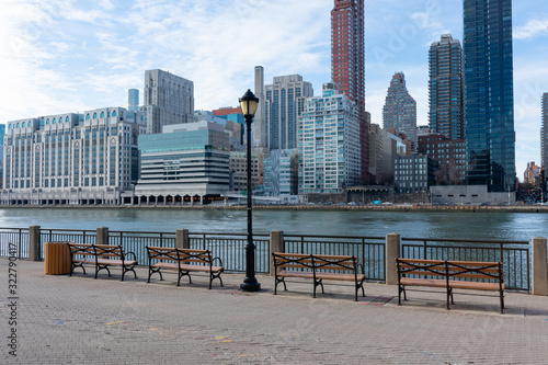 Row of Benches along the East River at Roosevelt Island and looking towards the Upper East Side Skyline of New York City © James