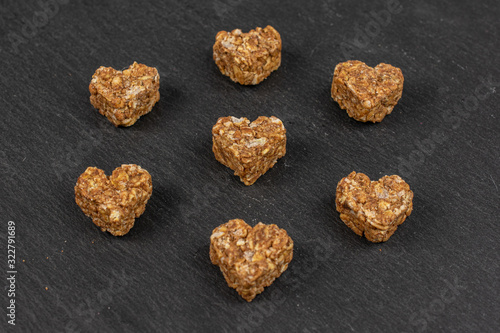 Group of seven whole healthy brown cereal heart with cocoa on grey stone