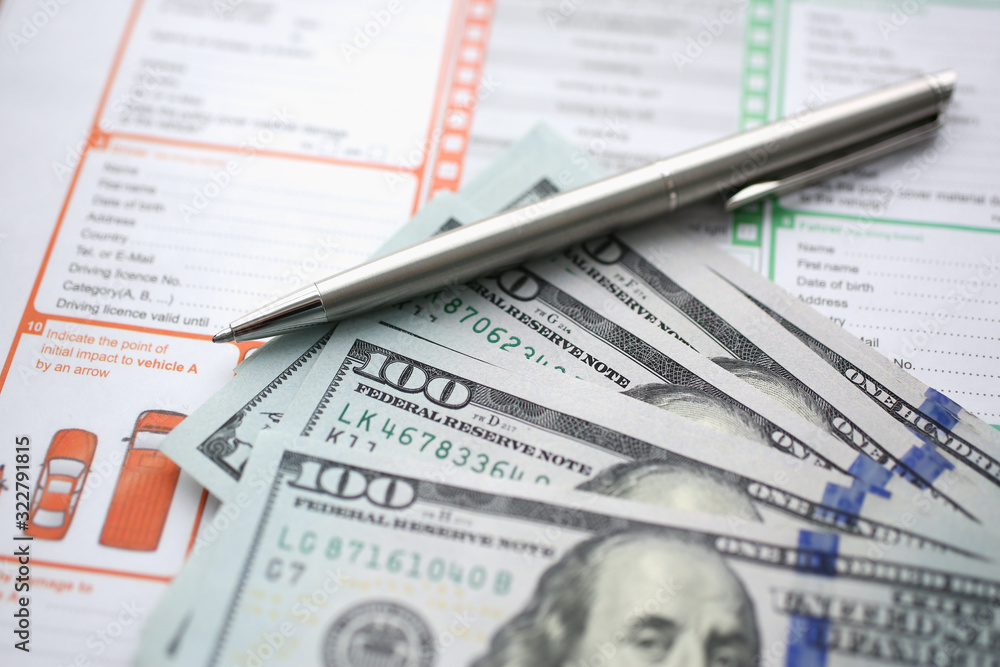 The silver pen with dollar banknotes is on the international euro-protocol form for filling and indemnification as a result of a traffic accident without police participation concept. The silver pen with dollar banknotes is on the international euro-protocol form for filling and indemnification as a result of a traffic accident without police participation concept.