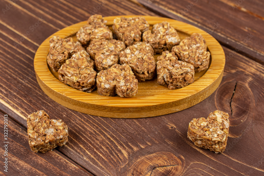 Lot of whole healthy brown cereal heart with cocoa on bamboo coaster on brown wood Lot of whole healthy brown cereal heart with cocoa on bamboo coaster on brown wood