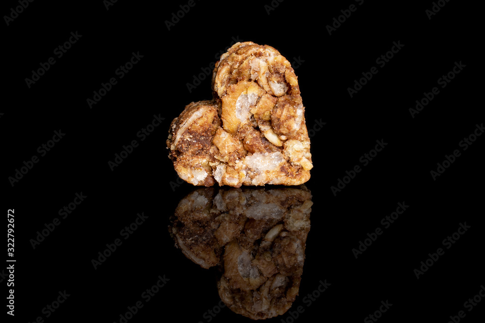 One whole healthy brown cereal heart with cocoa isolated on black glass