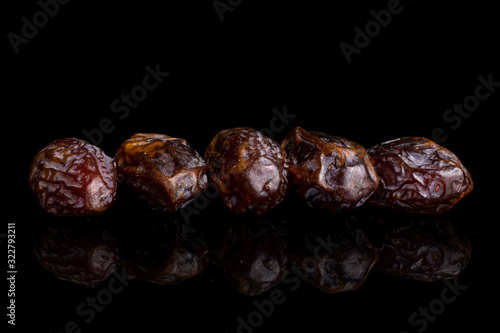 Group of five whole dry brown date fruit isolated on black glass