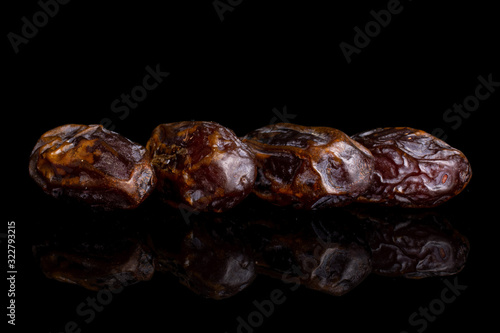 Group of four whole dry brown date fruit isolated on black glass
