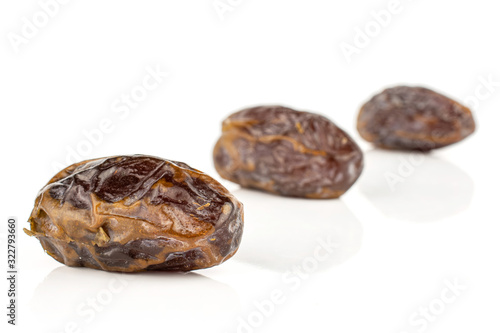 Group of three whole dry brown date fruit placed diagonally isolated on white background