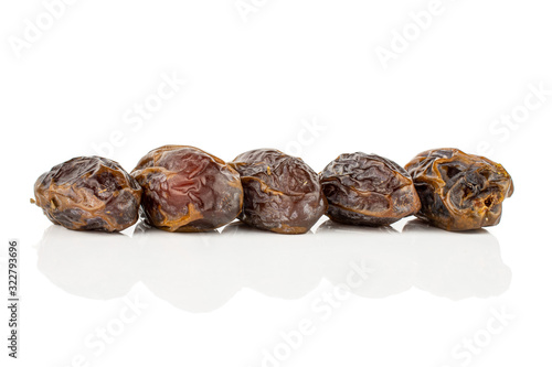 Group of five whole dry brown date fruit isolated on white background