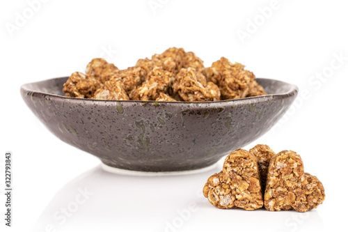 Lot of whole healthy brown cereal heart with cocoa in dark ceramic bowl isolated on white background