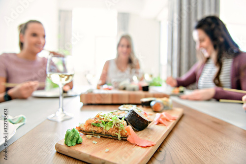 Focus on sushi with a Group of attractive mature people eating sushi at home on the back