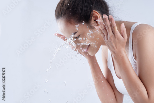 Valokuva Beautiful woman washing her face in a white background studio