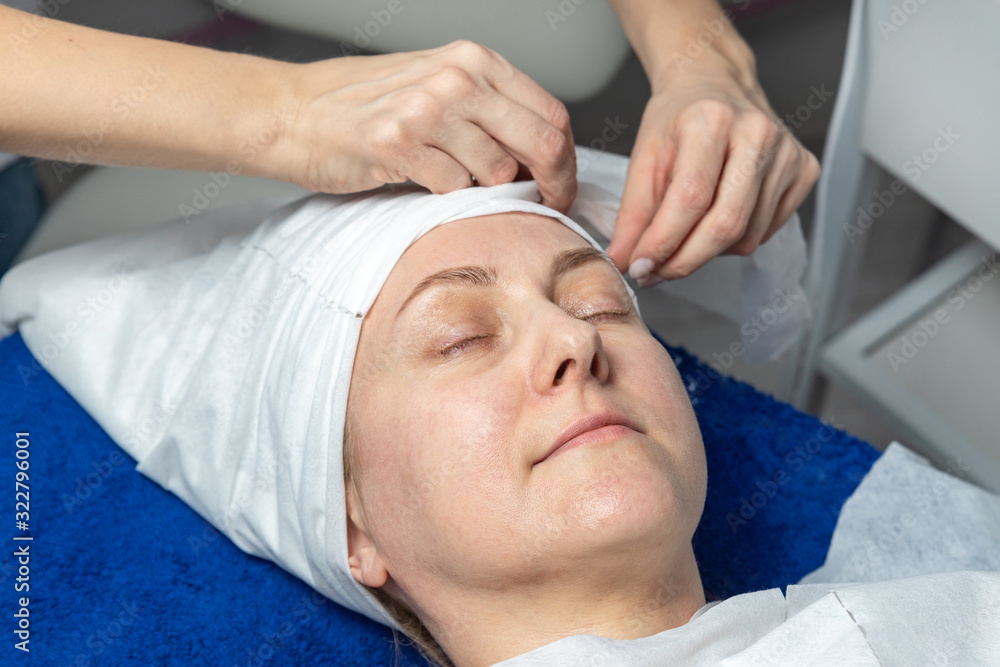 Close-up beautician doctor hands making anti-age procedures, applying foam cleansing mask for mid-aged female client at beauty clinic. Cosmetologist doing skincare treatment .Health care therapy Close-up beautician doctor hands making anti-age procedures, applying foam cleansing mask for mid-aged female client at beauty clinic. Cosmetologist doing skincare treatment .Health care therapy