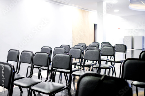 Black chairs stand in even rows in the classroom. Room for lectures. Without people