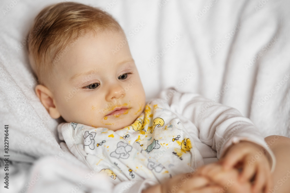 Feeding a baby vegetable puree. Dirty baby. The concept of childhood, first lure and baby food. Feeding a baby vegetable puree. Dirty baby. The concept of childhood, first lure and baby food.