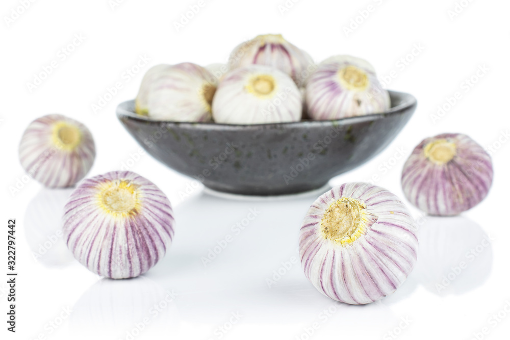 Lot of whole fresh purple single clove garlic in dark ceramic bowl isolated on white background Lot of whole fresh purple single clove garlic in dark ceramic bowl isolated on white background