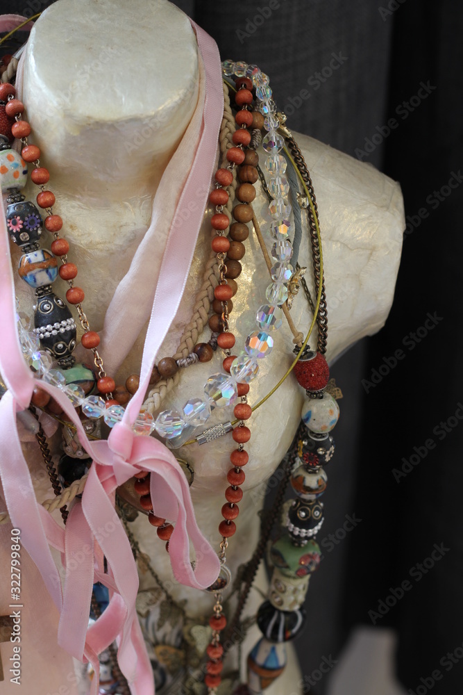 A collection of beads, necklaces and ribbons on a bust of a tailors dummy , a decorative feature  
