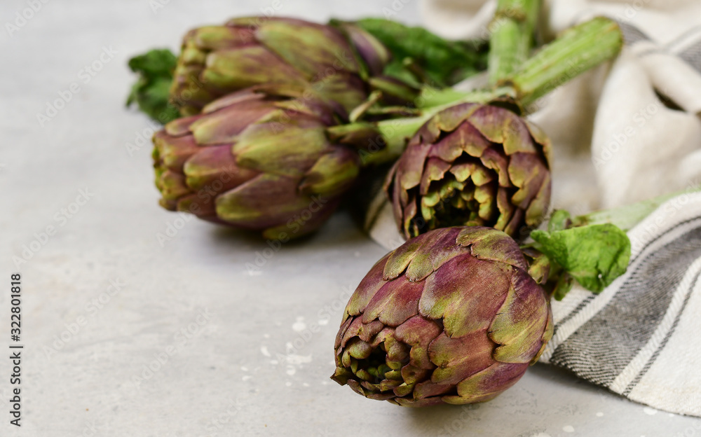 Fototapeta premium Fresh artichokes on a light stone table. . organic seasonal vegetables. artichoke recipe. selective focus