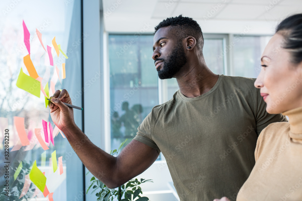 Ταπετσαρία A young African man and an Asian woman brainstorming ideas in the office