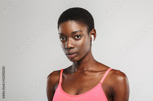 Image of african american sportswoman using wireless earbuds