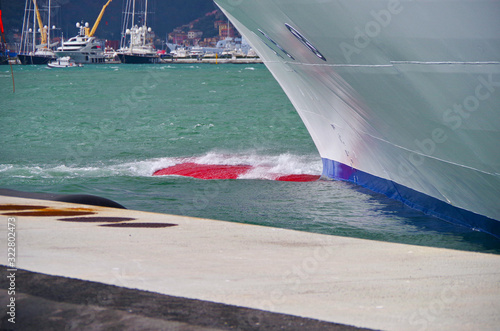 Bulbous Bow of cruiseship or cruise ship liner with waves in port on windy day photo