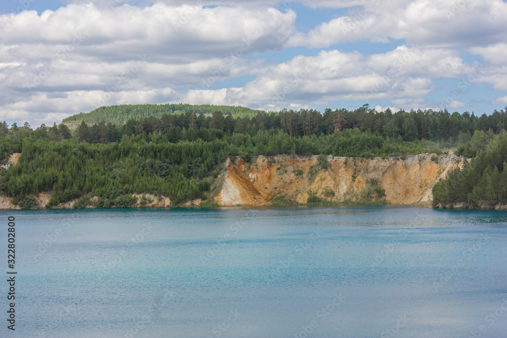 Flooded emerald quarry lake with blue water landscape Flooded emerald quarry lake with blue water landscape