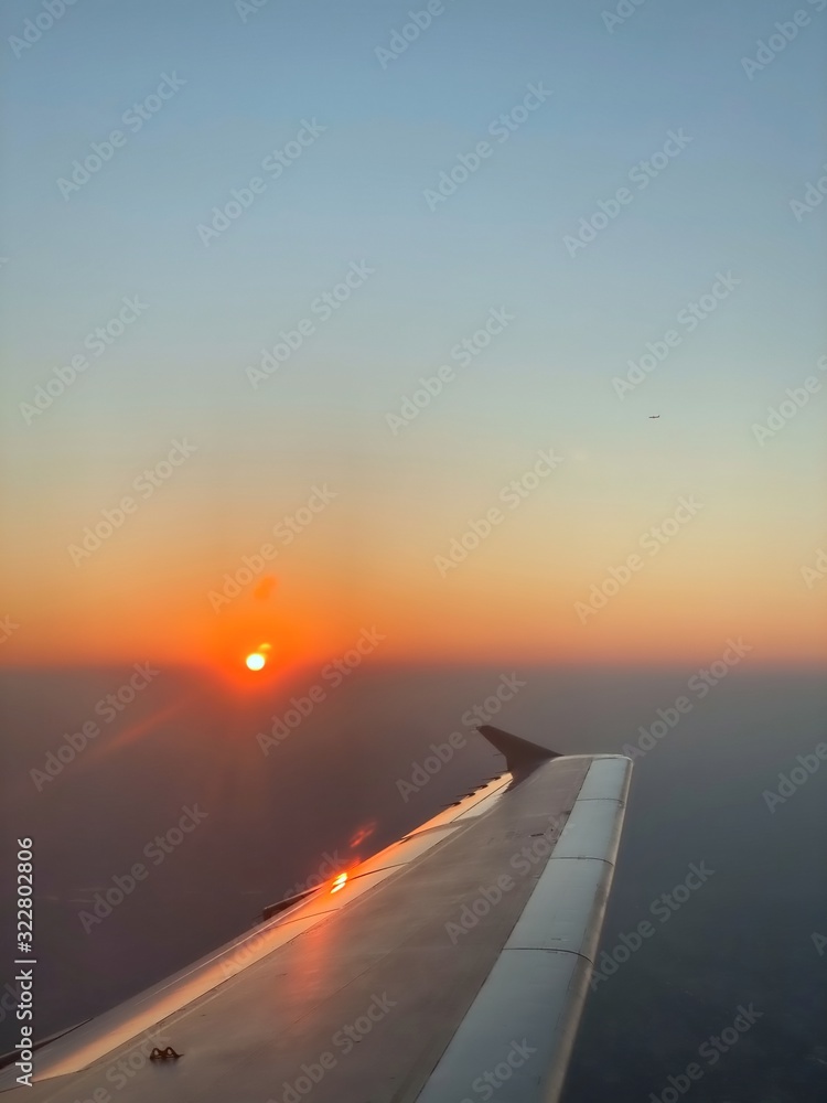 Obraz premium The air plane wing in the sky with sunset in the horizon