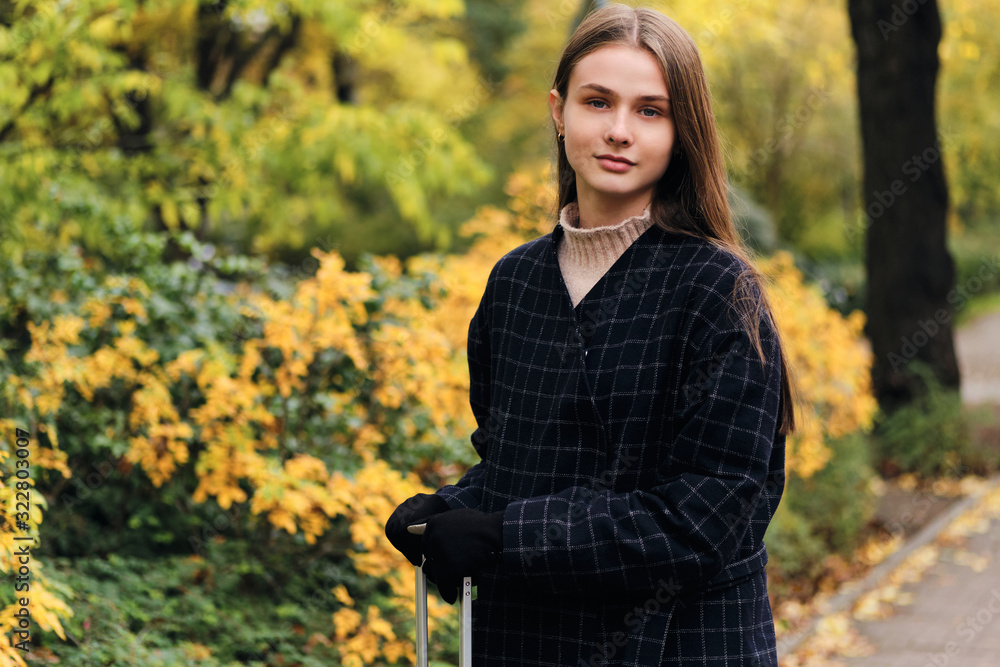 Beautiful stylish girl in coat confidently looking in camera in park Beautiful stylish girl in coat confidently looking in camera in park