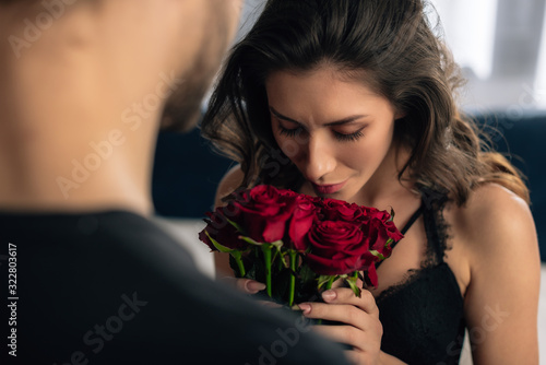 cropped view of attractive girlfriend smelling roses from boyfriend in 14 february