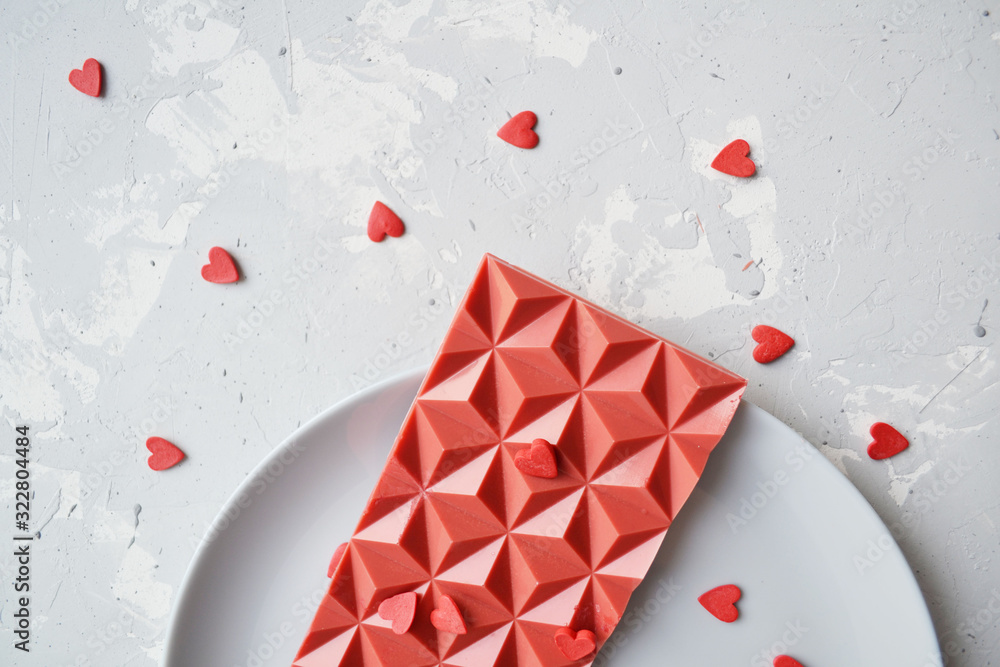 red chocolate bar, scattered small hearts on a white background. background for Valentine's day red chocolate bar, scattered small hearts on a white background. background for Valentine's day