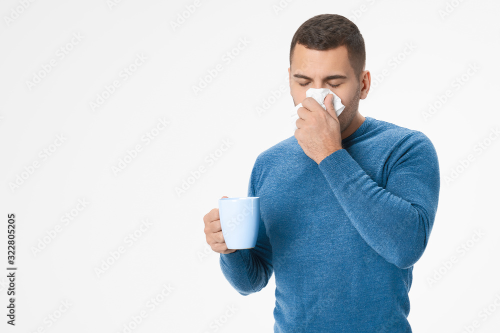 Sick unhealthy young man holding paper tissue sneezing blowing with cup on white background Sick unhealthy young man holding paper tissue sneezing blowing with cup on white background