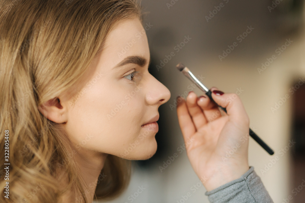 Makeup artist work in her beauty studio. Portrait of Woman applying by professional make up master. Beautiful make up artist start making a makeup for blond hair model Makeup artist work in her beauty studio. Portrait of Woman applying by professional make up master. Beautiful make up artist start making a makeup for blond hair model