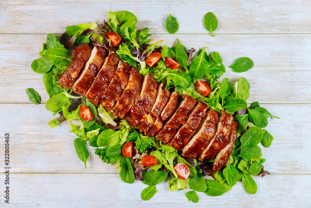 Cuts pork loin fillet serve with green salad and tomatos.